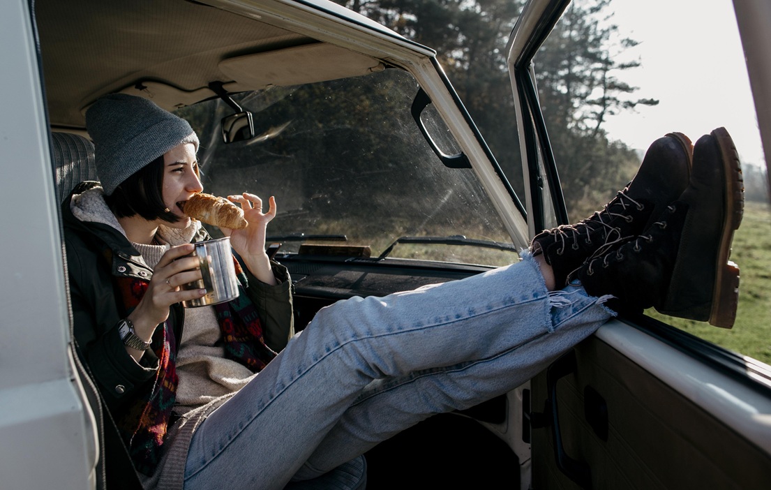 mujer comiendo y bebiendo cafe en una camioneta