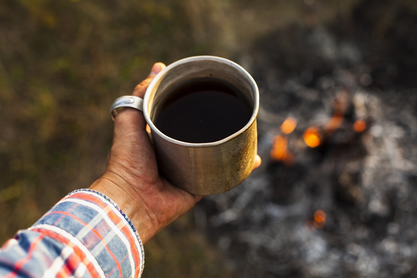 taza de cafe en el exterior cerca de una fogata